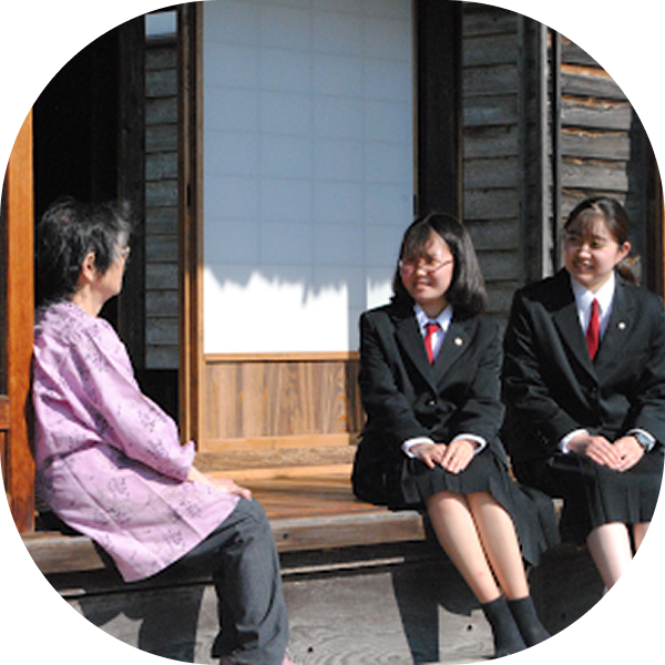 縁側で地域の人と談笑している女子高生の様子